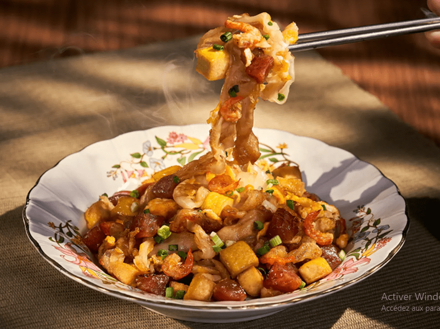 Steaming bowl of Cry Baby Noodles garnished with fresh herbs and chili.
