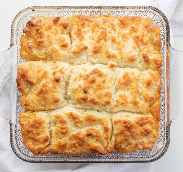 Freshly baked butter swim biscuits on a rustic wooden table.