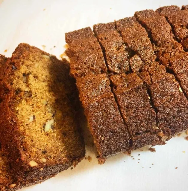 Sliced persimmon bread on a wooden board with fresh persimmons on the side